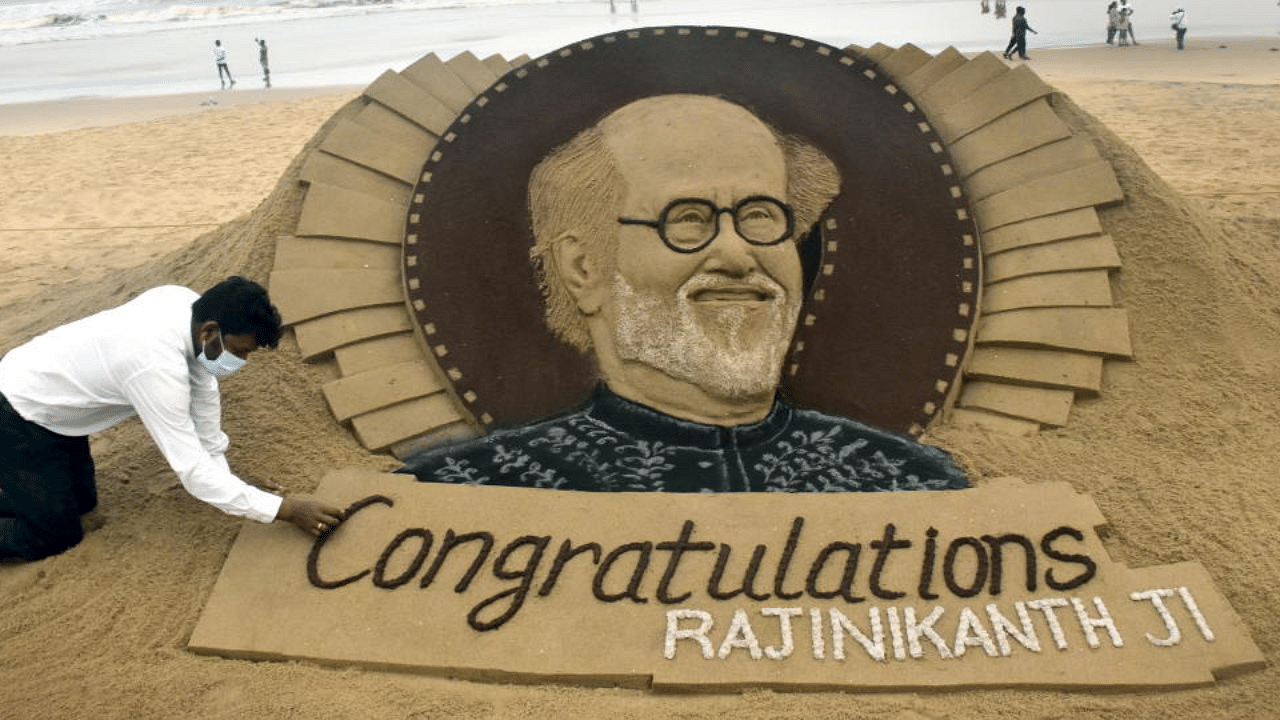 Artist Sudarshan Pattnaik gives finishing touches to a sand sculpture congratulating superstar Rajinikanth in Puri. Credit: PTI Photo