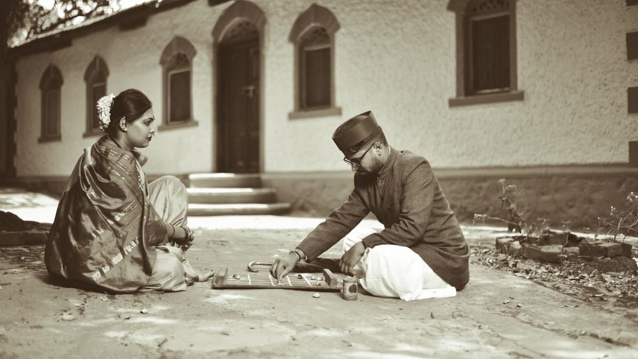 Chetana and Nikhil in the attire of Laxmibai and Da Ra Bendre playing chowka baara (a game with cowry shells) during their pre-wedding shoot in Dharwad. Credit: DH Photo