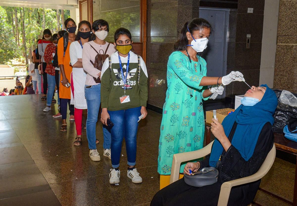 A medic collects swab sample of students for the COVID-19 test following a surge in coronavirus cases, at NMKRV PU College in Bengaluru. Credit: PTI photo.