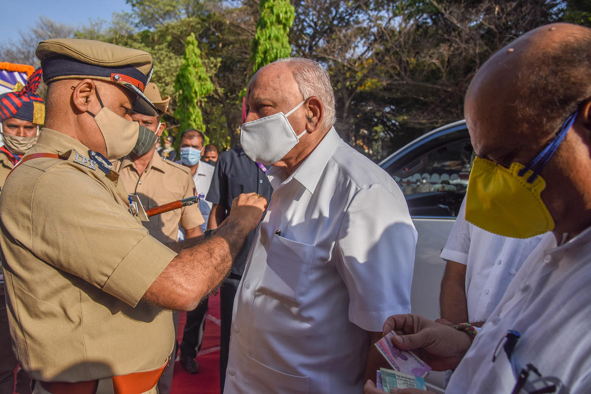 Praveen Sood DG and IGP pining flag to B S Yediyurappa, Chief Minister at Karnataka State Police Flag day celebration organised by DG and IGP Karnataka State Police at KSRP Parade Ground, Koramangala in Bengaluru on Friday. Credit: DH photo.