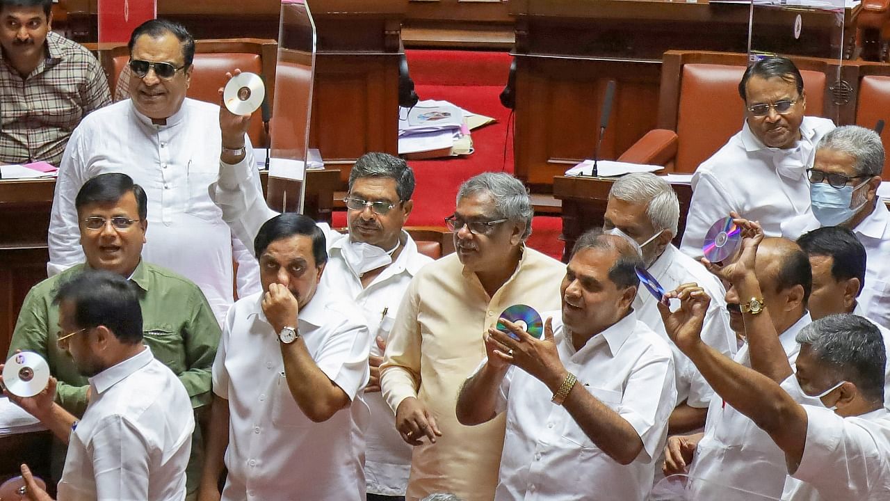 Congress legislators protest inside the Well of the House demanding action against BJP leader Ramesh Jarkiholi for his alleged involvelemnt in a sex tape scandal, during the Karnataka Budget Session, at Vidhana Soudha in Bengaluru. Credit: PTI File Photo