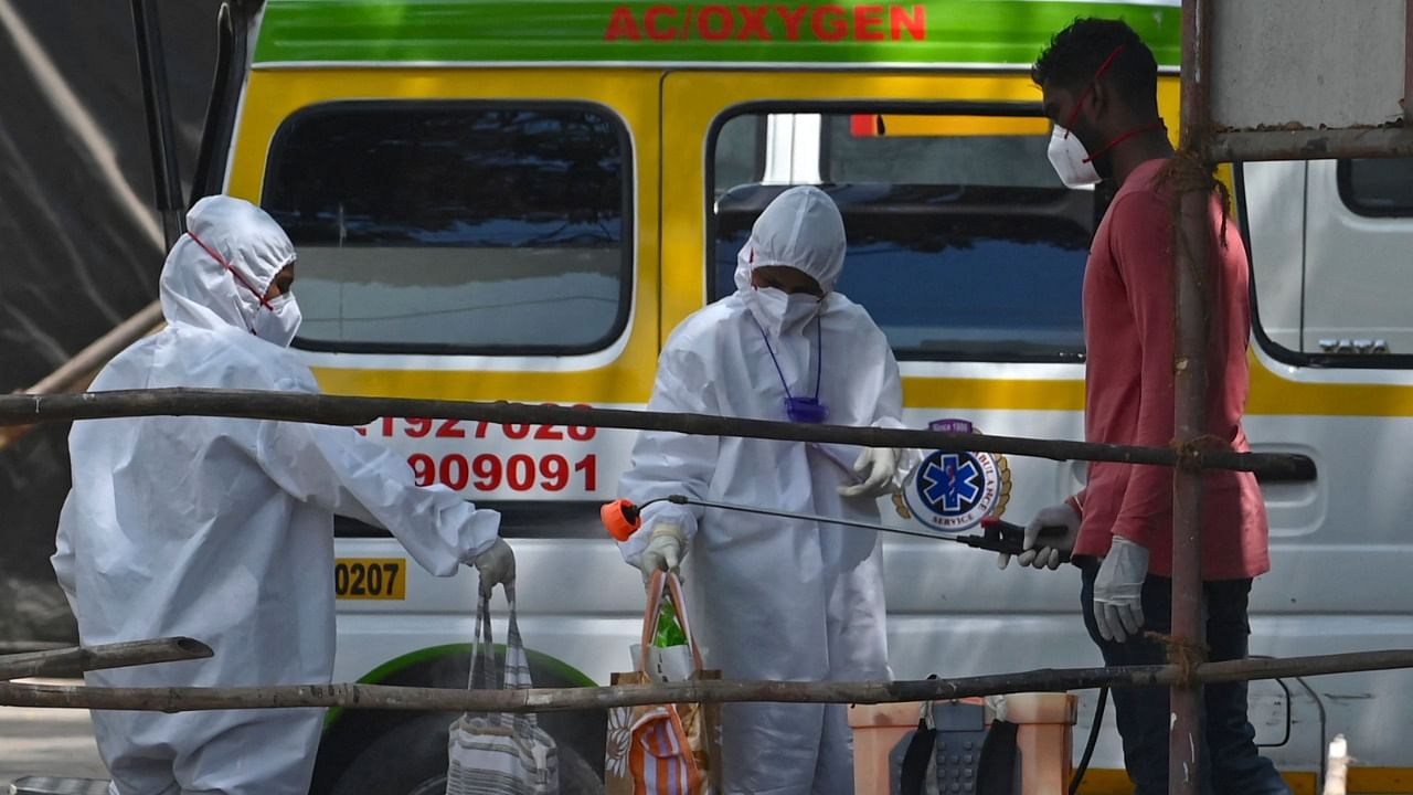 A health worker sanitises the bags of a recovered patient held by medical staff wearing protective gear inside the premises of a Covid-19 coronavirus quarantine centre in Mumbai. Credit: AFP.
