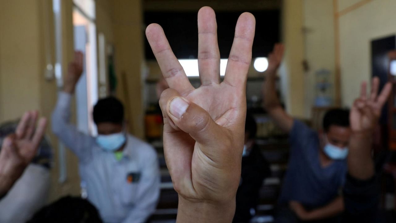 Myanmar nationals including those who said they are police and firemen and recently fled to India flash the three-finger salute at an undisclosed location. Credit: Reuters.