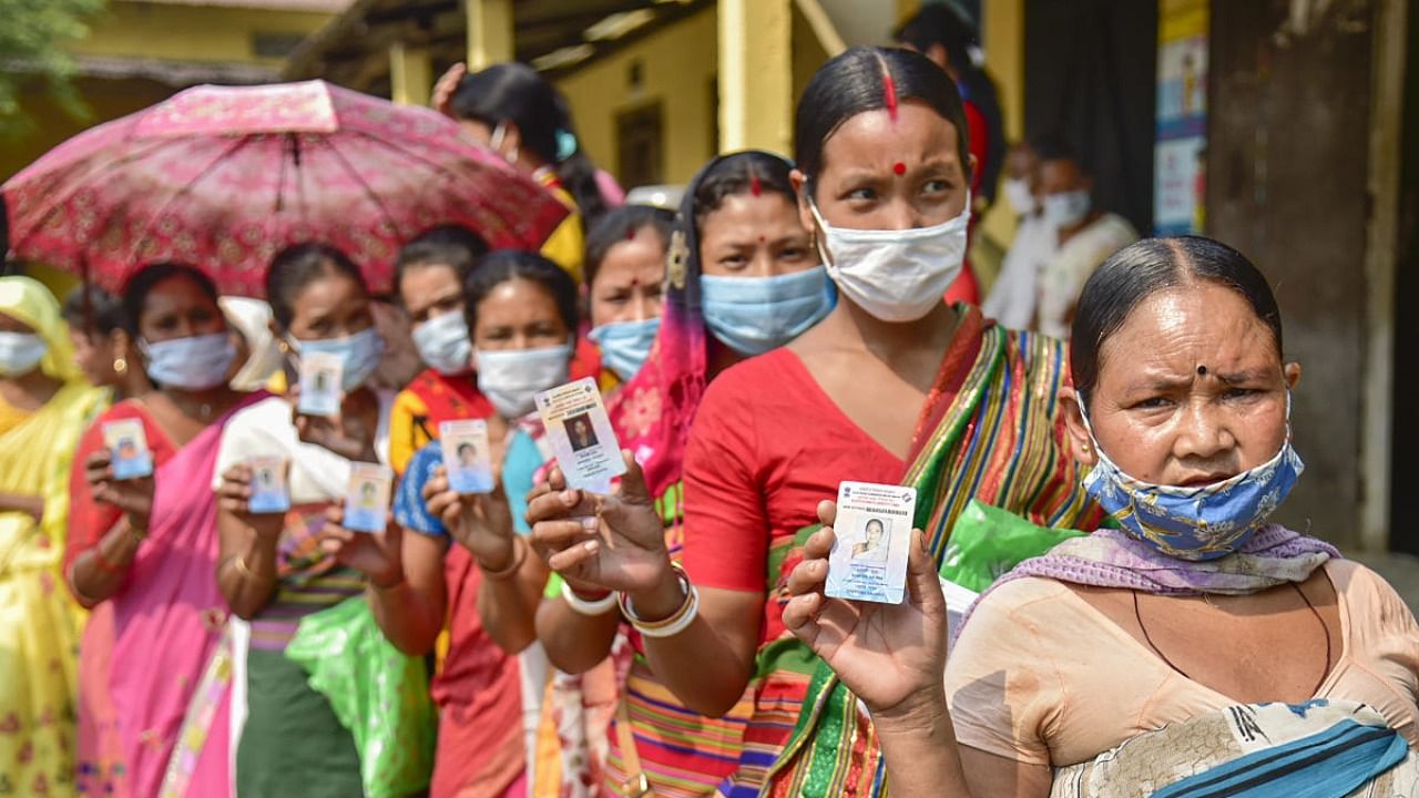 Hajong tribal women show their voter identity cards as they wait in the queue to cast their votes at a polling Station for Assembly polls, at Boko in Kamrup district. Credit: PTI Photo