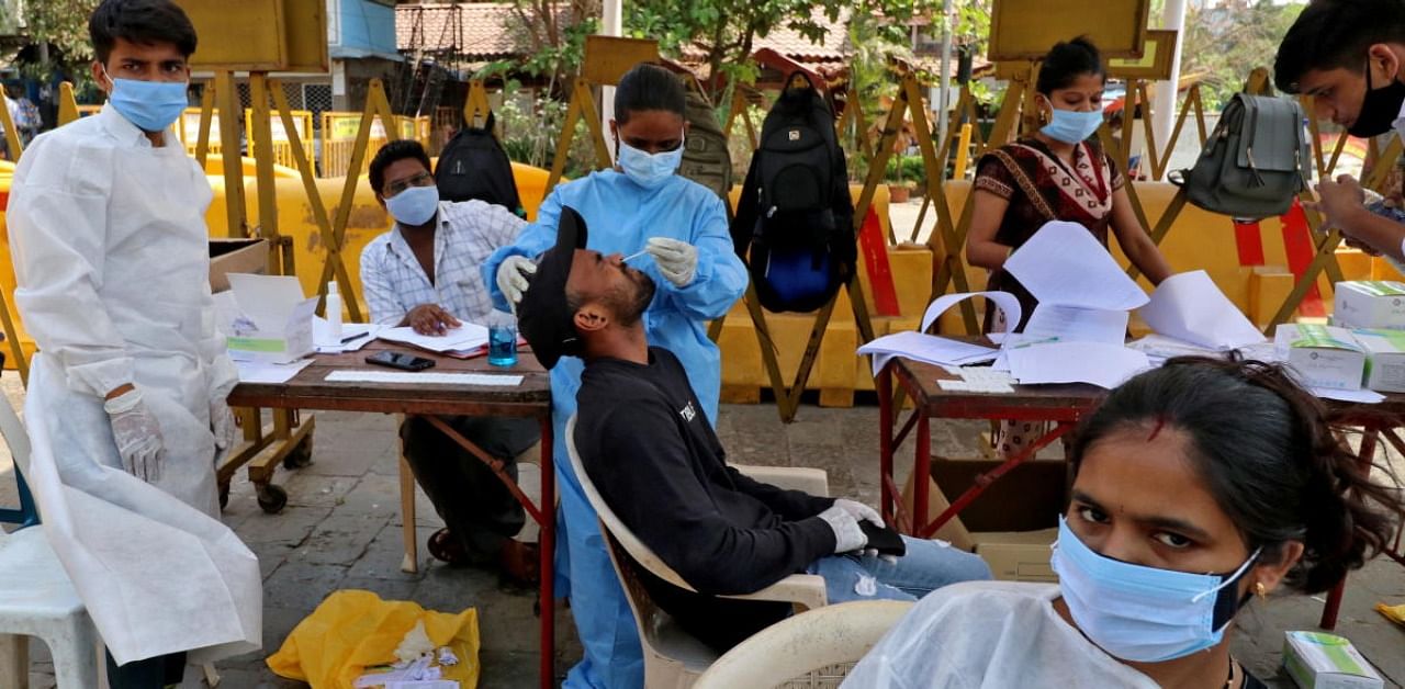 A healthcare worker collects a swab sample from a man during a rapid antigen testing campaign for the coronavirus disease (Covid-19), in Mumbai. Credit: Reuters Photo