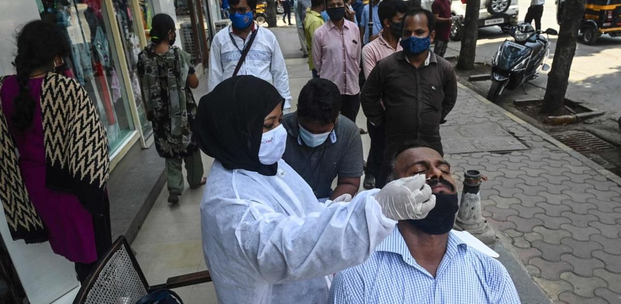 A health worker takes a swab sample for a Rapid Antigen Testing (RAT) at a roadside market following restrictions imposed by the state government amidst rising Covid-19 coronavirus cases, in Mumbai. Credit: AFP Photo