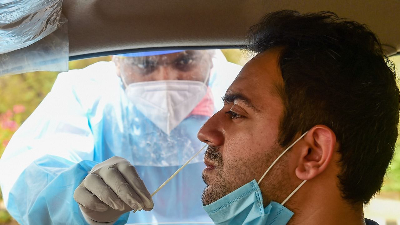 A health worker collects samples of a motorist for Covid-19 tests, as coronavirus cases spike across the country, in New Delhi. Credit: PTI Photo