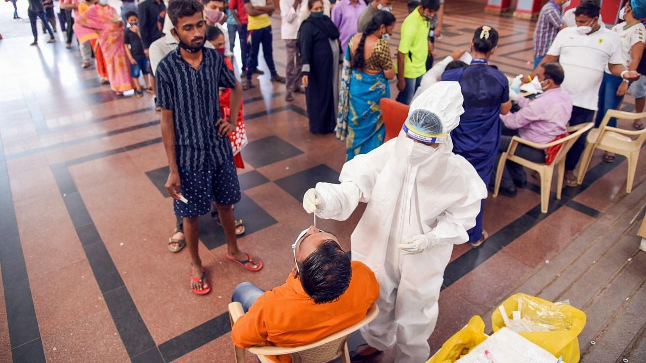 Medics collect swab samples of passengers for Covid-19 tests as the cases spike across the country at Kopar Khairane Railway Station in Navi Mumbai, Monday, April 5, 2021. Credit: PTI Photo