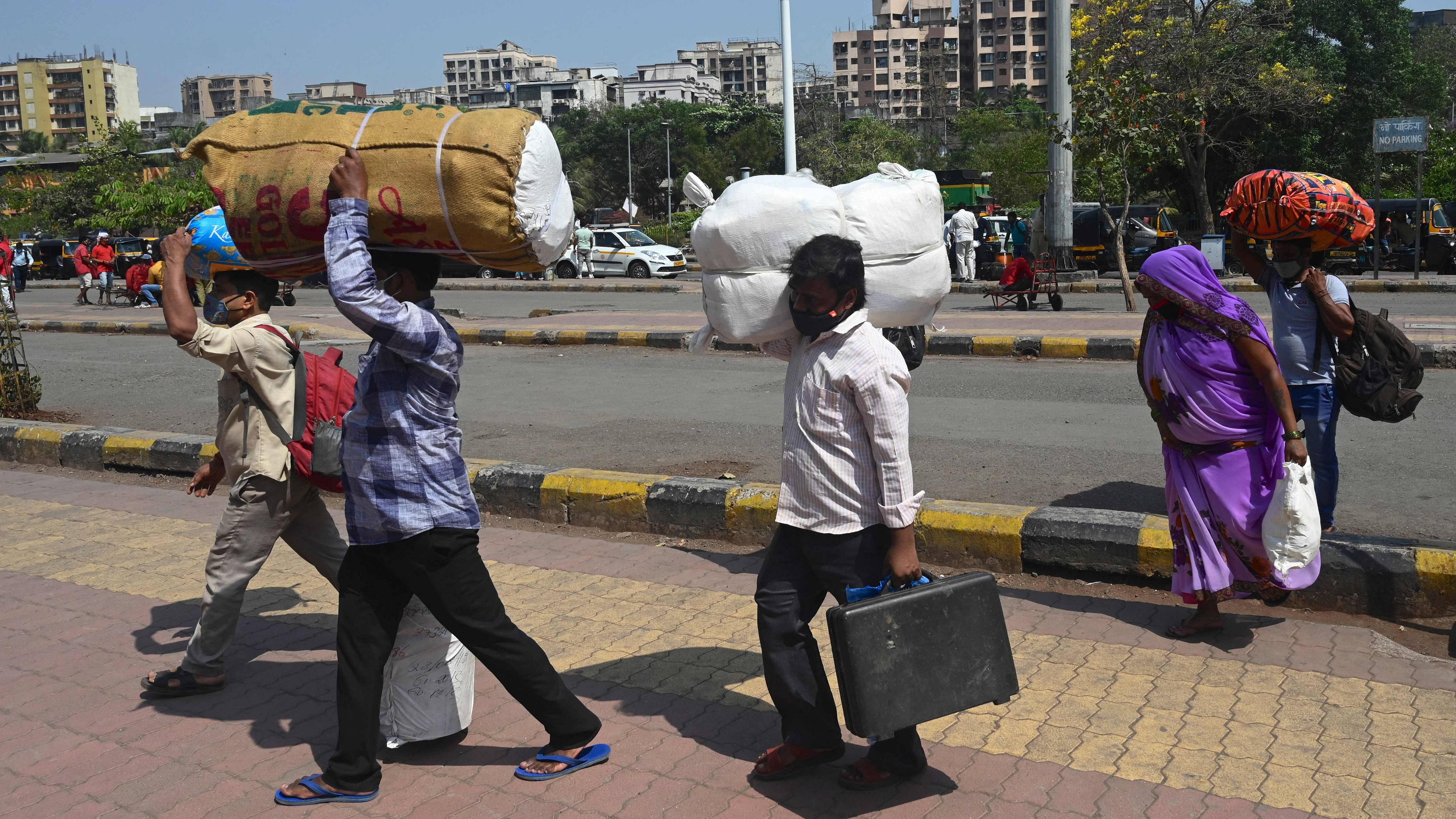 Passengers walk with their luggage outside Lokmanya Tilak Terminus railway complex to catch a train amidst rising Covid-19 coronavirus cases in Mumbai. Credit: AFP File Photo
