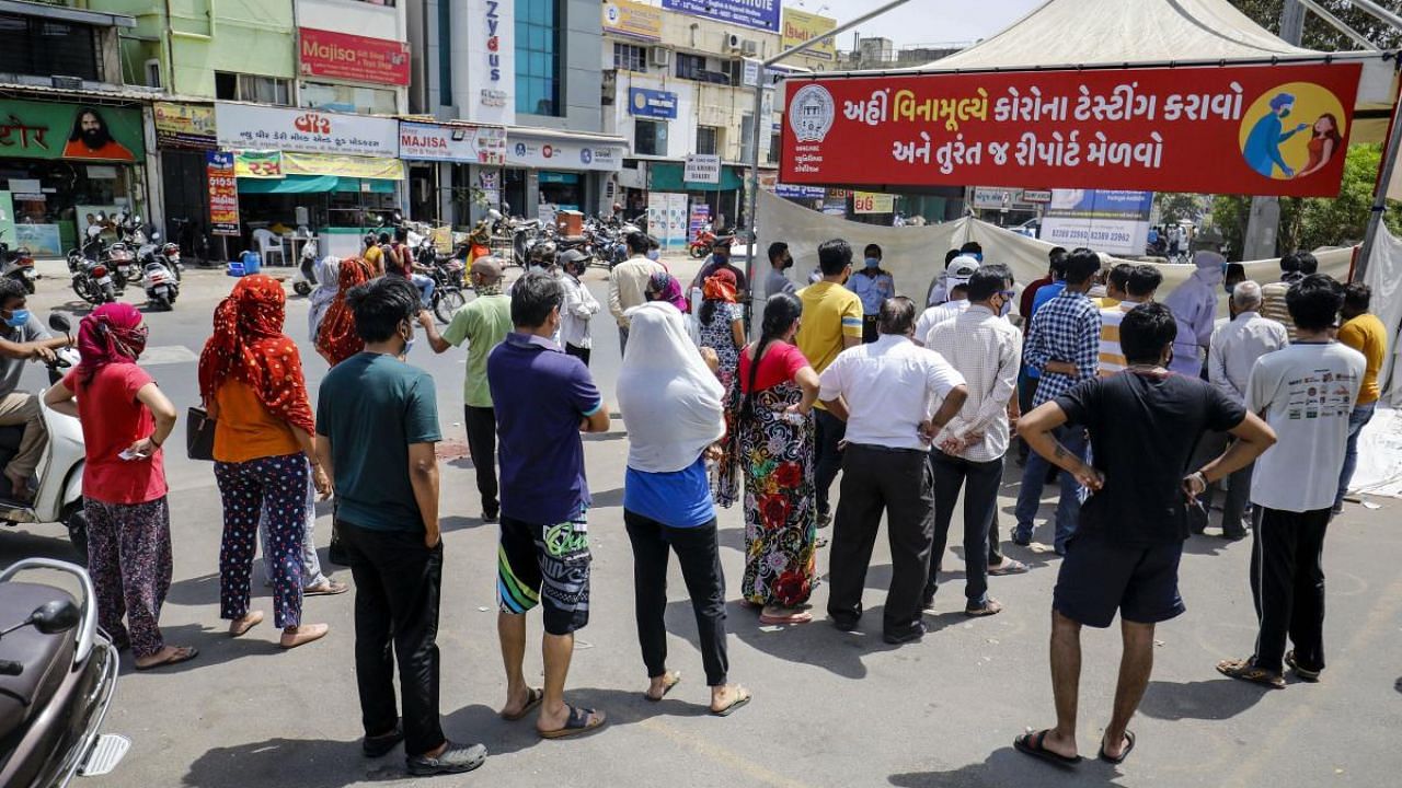 People wait in a queue for their Covid-19 tests, at roadside testing camp in Ahmedabad. Credit: PTI photo. 