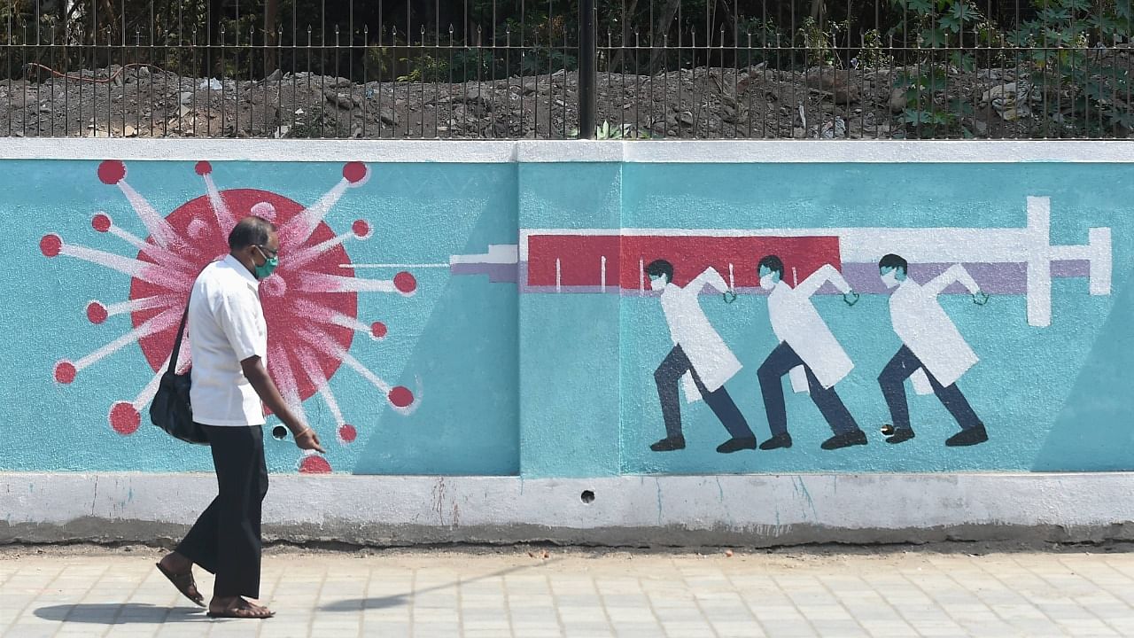A man walks past a graffiti depicting coronavirus, amid a countrwide spike in cases, in Mumbai, Tuesday, April 6, 2021. Credit: PTI Photo