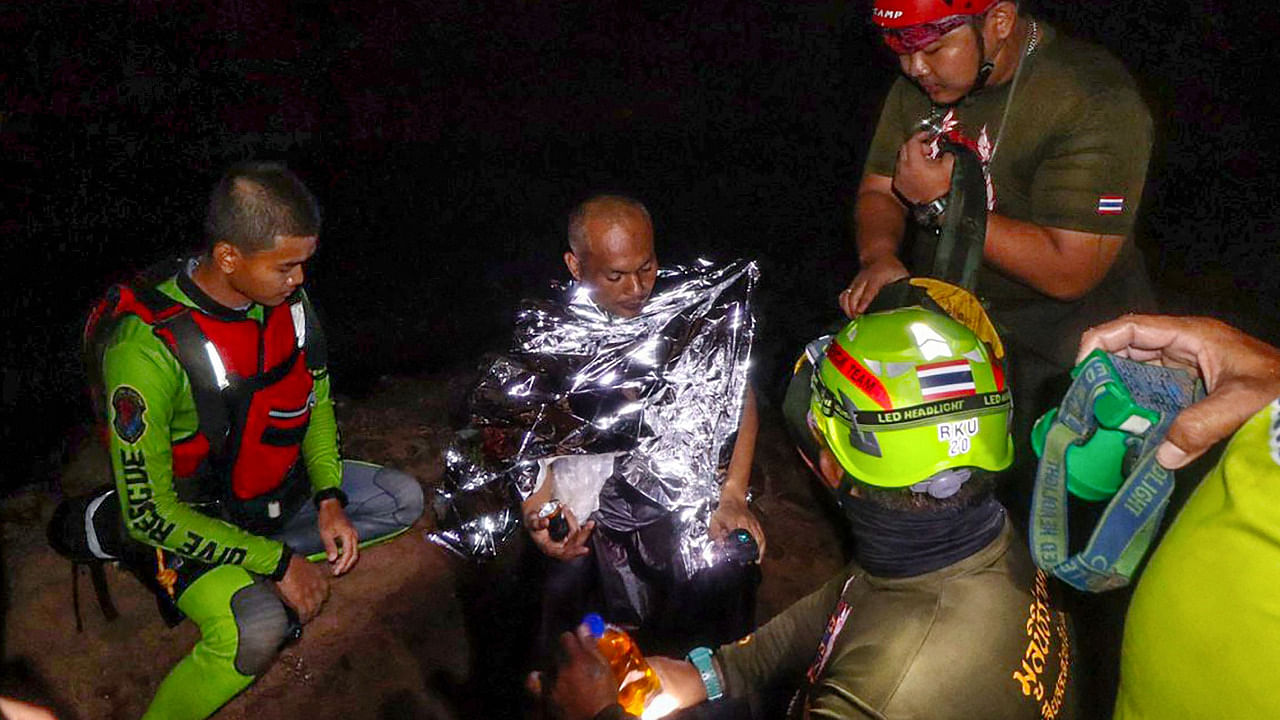 Buddhist monk Manas Kemgoh (2nd L), who had been trapped in a flooded cave while meditating, surrounded by rescue workers in Phra Sai Ngam cave in Thailand's Phitsanulok province. Credit: AFP Photo