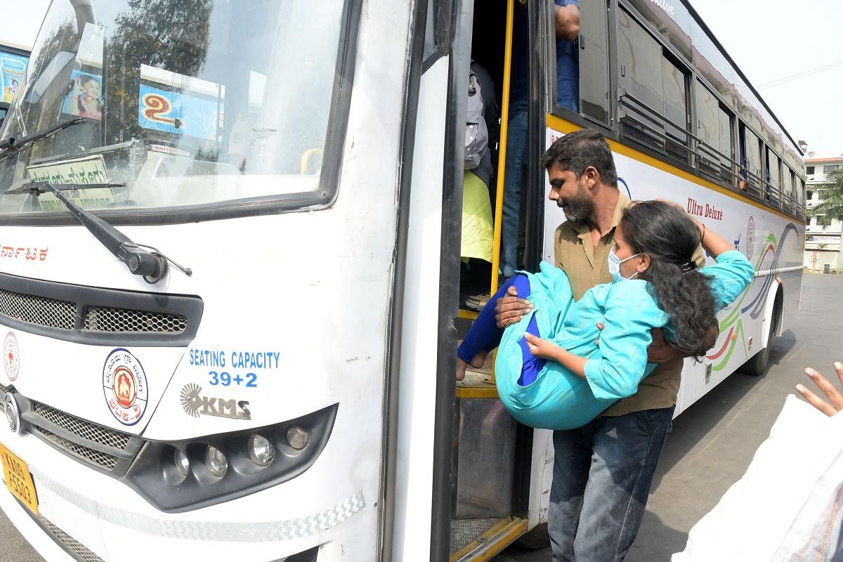 A man helps a physically challenged woman to board a KSRTC bus in Mysuru on Thursday. DH PHOTO