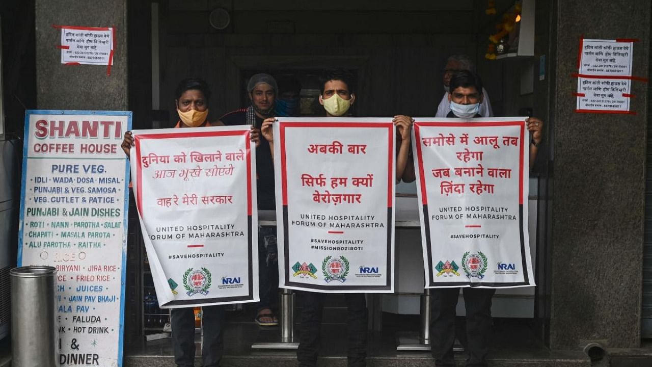 Restaurant staff hold posters protesting new restrictions allowing only tRestaurant staff hold posters protesting new restrictions allowing only takeaway orders imposed by state government amidst rising Covid-19 coronavirus cases, outside a restaurant in Mumbai on April 8, 2021. Credit: AFP Photo