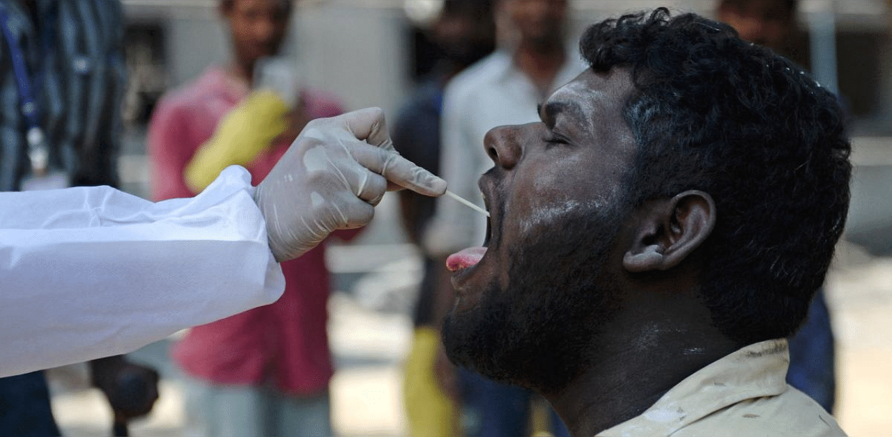 A health worker takes a swab sample of a man for conducting RT-PCR Covid-19 test at a construction site in Chennai. Credit: AFP photo.