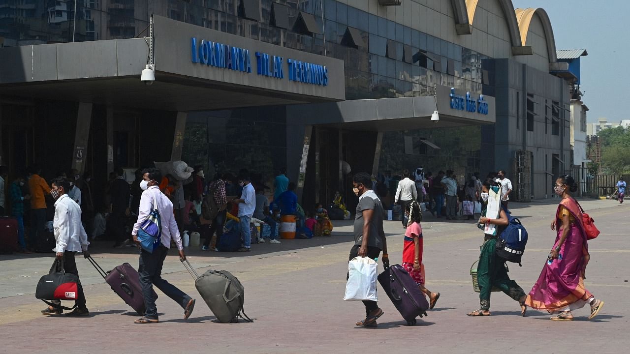 Passengers walk with their luggage outside Lokmanya Tilak Terminus railway complex to catch a train amidst rising Covid-19 coronavirus cases Mumbai. Credit: AFP File Photo