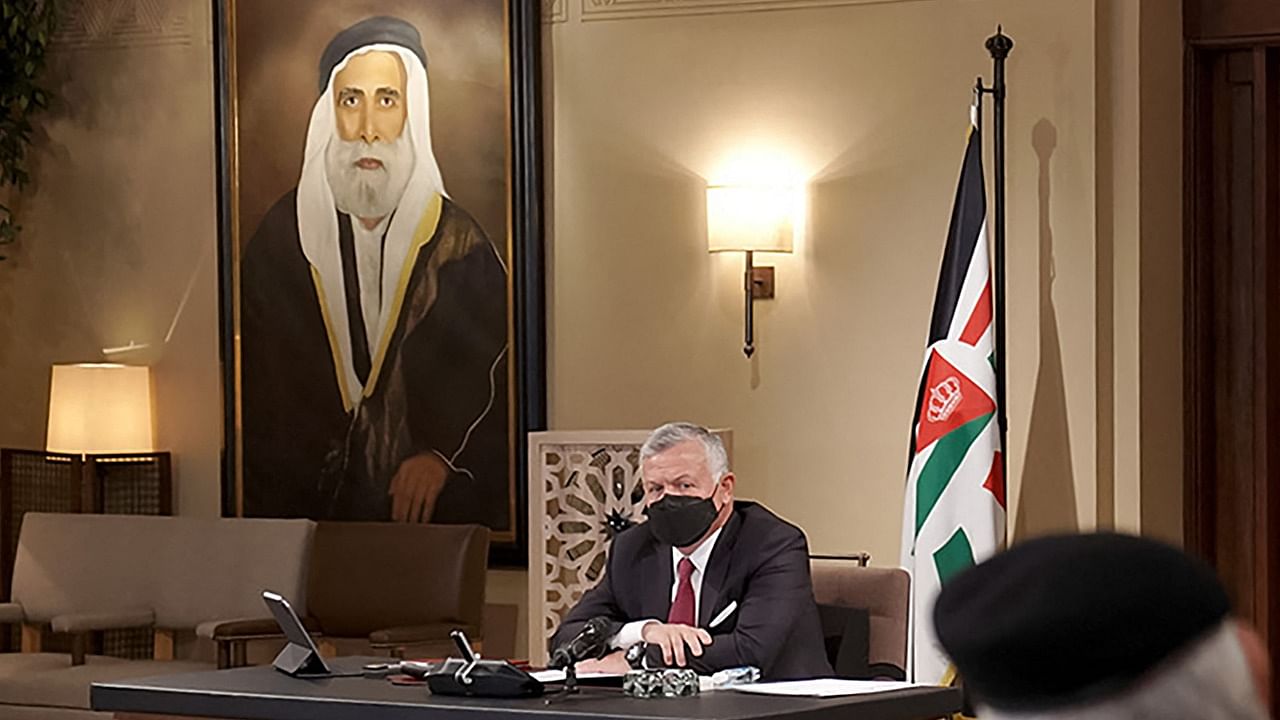 This file handout picture released by the Jordanian Royal Palace on 15, 2021 shows Jordan's King Abdullah II chairing a meeting with armed forces' commanders, including his son Crown Prince Hussein (unseen), to discuss programs supporting retired servicemen and veterans, while behind is seen a hanging portrait of his ancestor Sharif Hussein bin Ali of Mecca. Credit: AFP Photo