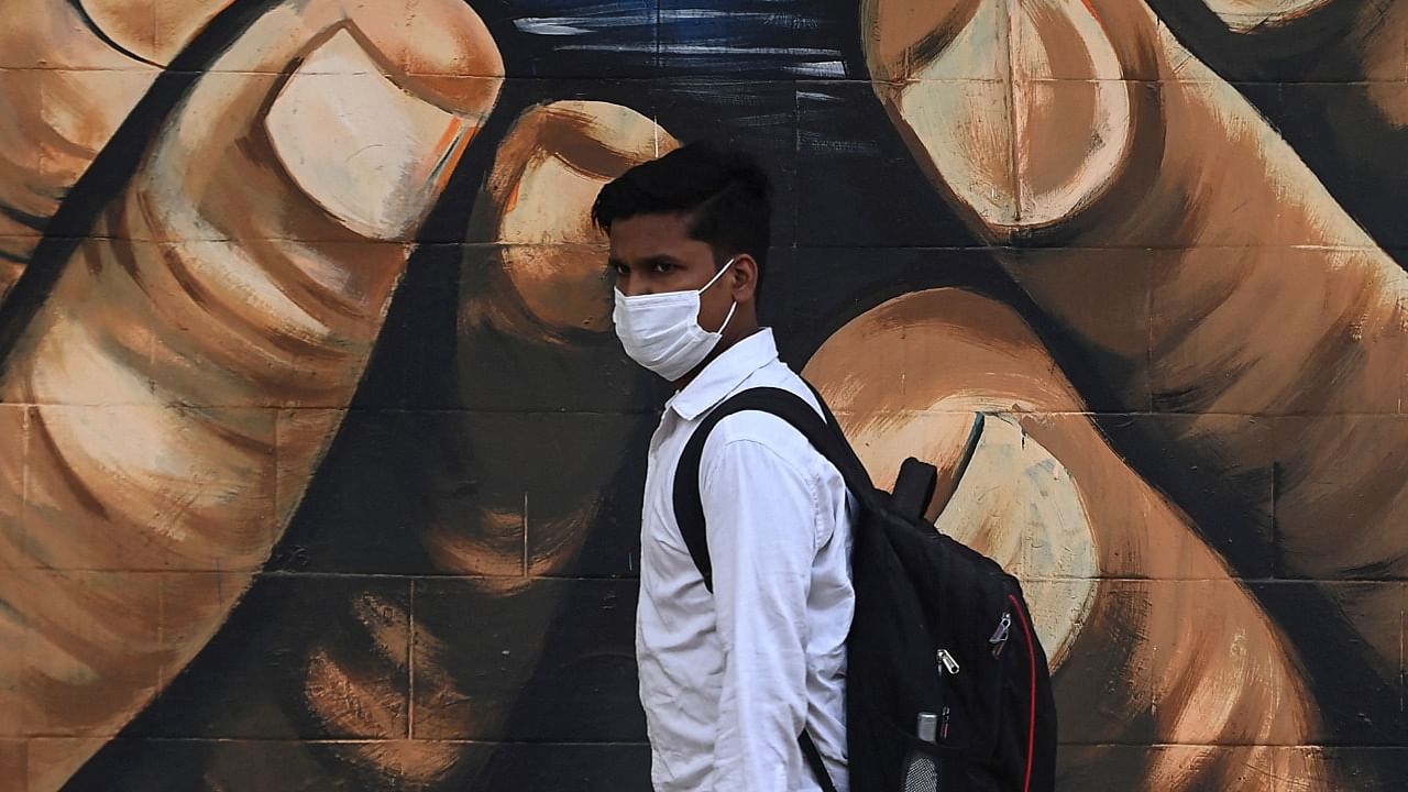 A man wearing a face mask as preventive measure against the Covid-19 coronavirus, walks past a graffiti wall in New Delhi. Credit: AFP file photo.
