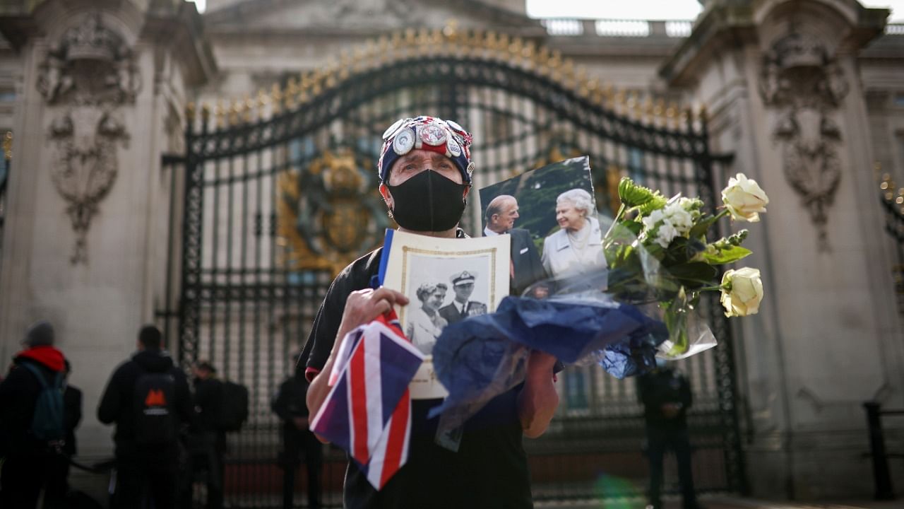 Britain mourns the death of Prince Philip A mourner holds flowers and pictures of Britain's Queen Elizabeth II and her husband Prince Philip outside Buckingham Palace, after Prince Philip died at the age of 99, in London. Credit: Reuters.