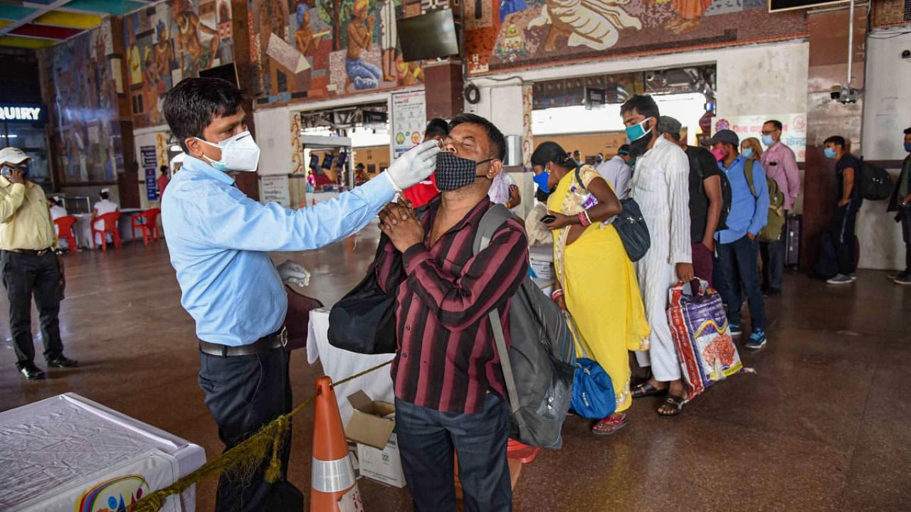 Health worker collect swab sample of a passenger arriving from Mumbai at Patna junction via special train, as coronavirus cases spike across the country, in Patna. Credit: PTI Photo