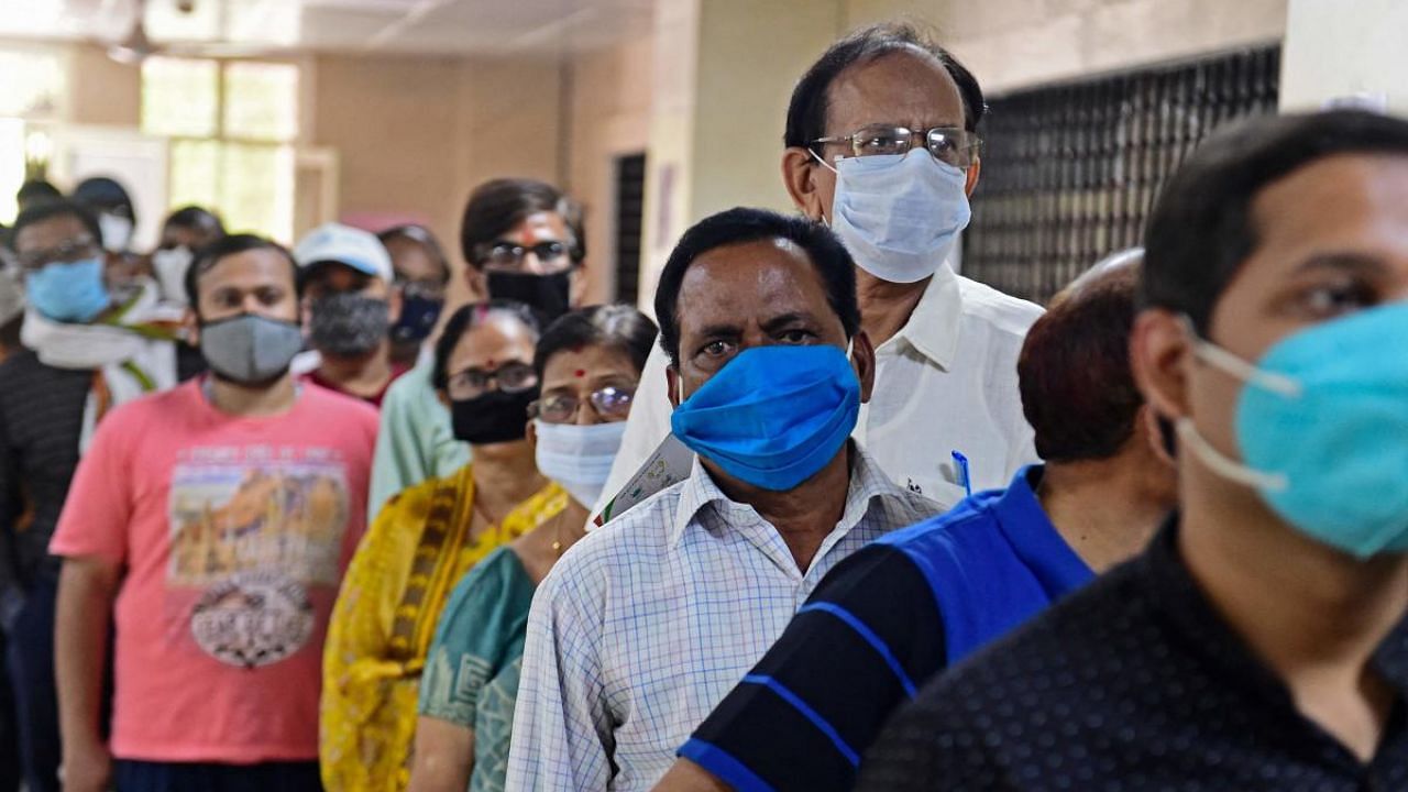People stand in a queue to receive the dose of the Covishield vaccine against the coronavirus at the Moti Lal Nehru Medical College in Allahabad. Credit: AFP photo. 