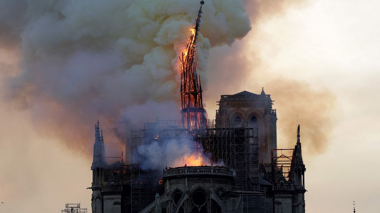 The steeple and spire of the Notre-Dame Cathedral collapses as the cathedral is engulfed in flames. Credit: AFP File Photo