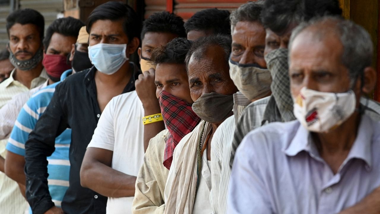 People stand in a queue as they wait for food to be distributed by social workers during weekend lockdown restrictions imposed by the state government amidst rising Covid-19 coronavirus cases, in Mumbai. Credit: AFP Photo