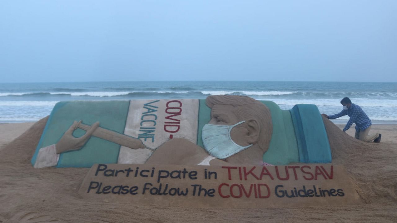 Artist Sudarshan Pattnaik gives finishing touches to a sand sculpture to create awareness of 'Tika Utsav', a vaccine festival called by Prime Minister Narendra Modi, in Puri. Credit: PTI Photo