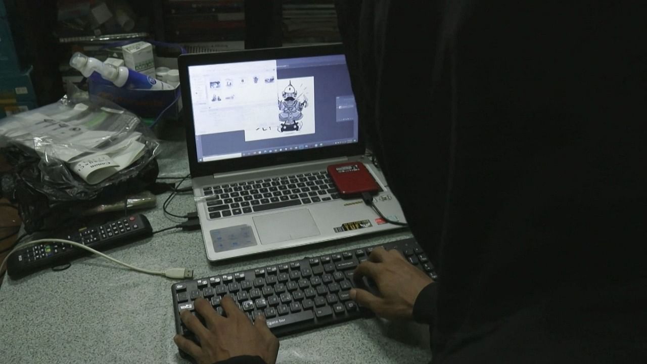 This screengrab provided via AFPTV video footage taken on April 10, 2021 shows Lynn Thant (an alias) working on an underground newsletter to spread information in Yangon, amid internet outages as demonstrations continue against the military coup. Credit: AFPTV / AFP photo