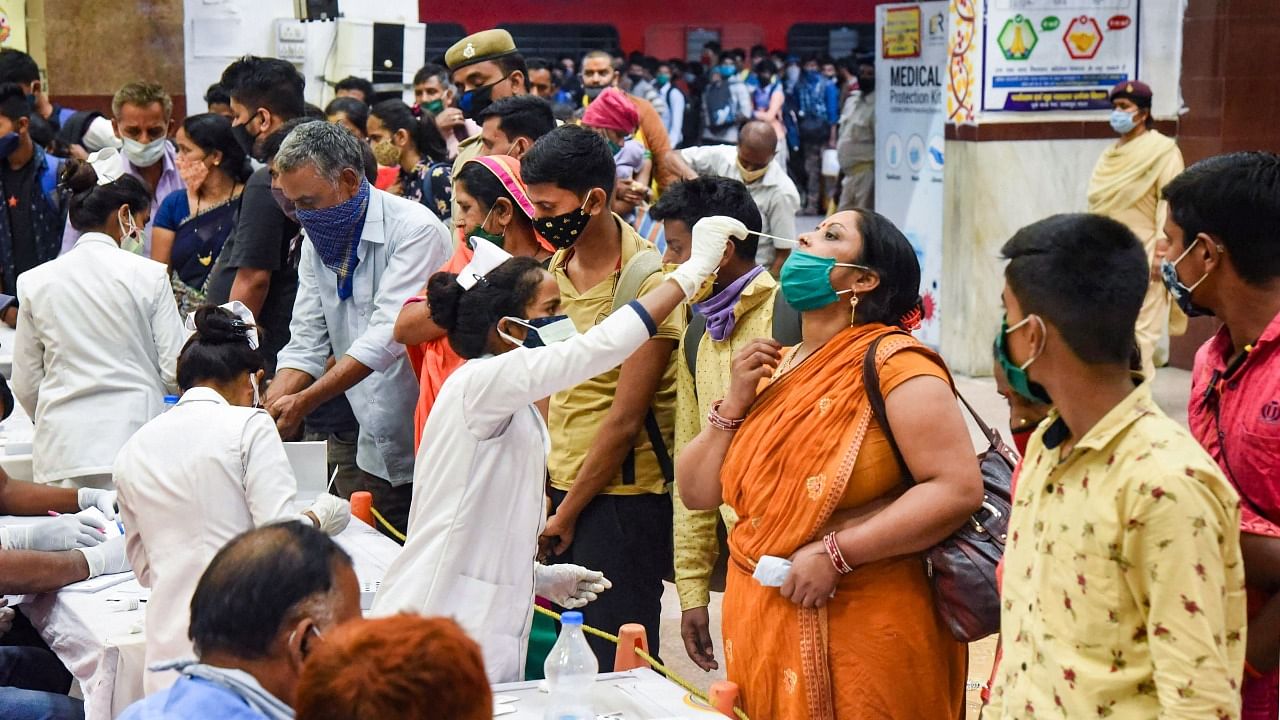 A health worker takes a swab sample of a migrant arriving from Maharashtra outside the Covid-19 testing counter, amid a rise in Covid-19 cases across the country at Patna railway station. Credit: PTI Photo