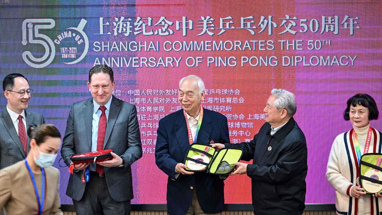This photo taken on April 10, 2021 shows US Consul General in Shanghai James Heller (2nd L) with former Chinese table tennis players and "ping-pong diplomacy" participants Zhang Xielin (centre L) and Zheng Minzhi (far R) receiving souvenirs during a ceremony to mark the 50th anniversary of the diplomatic event at the International Table Tennis Federation museum in Shanghai. Credit: AFP.