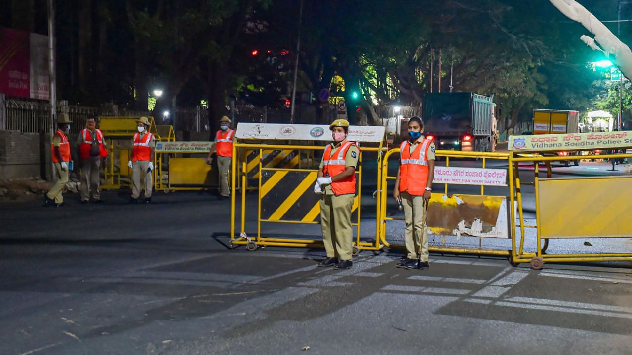Police install the barricades at M G road after the authorities announced the night curfew amid surge in coronavirus cases in Bengaluru. Credit: PTI photo. 
