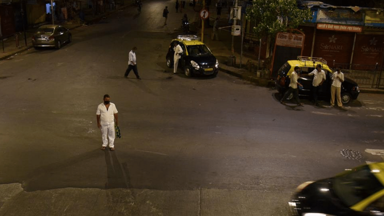 Commuters are pictured on a partially deserted road during a night curfew ahead of the scheduled weekend lockdown imposed by the state government amidst rising Covid-19 coronavirus cases in Mumbai. Credit: AFP Photo
