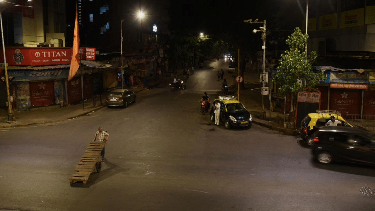 Commuters are pictured on a partially deserted road during a night curfew ahead of the scheduled weekend lockdown imposed by the state government amidst rising Covid-19 cases in Mumbai. Credit: AFP file photo. 