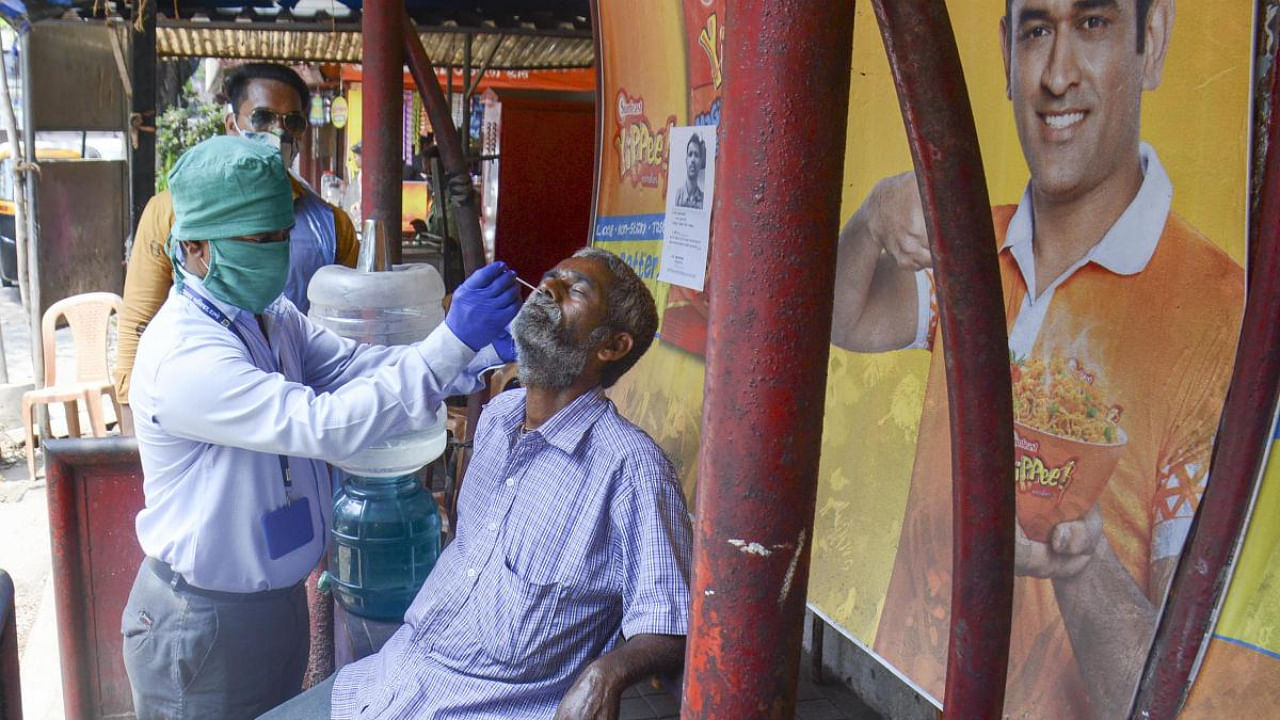 A medic takes a swab sample from a person for the Covid-19 test amid a surge in coronavirus cases, in Thane. Credit: PTI photo. 