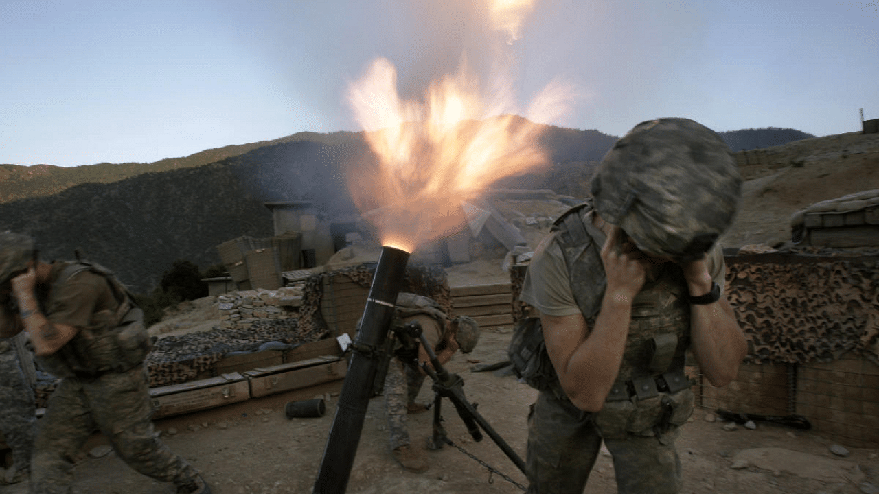 Soldiers from the US Army First Battalion, 26th Infantry fire mortars from the Korengal Outpost at Taliban positions in the Korengal Valley of Afghanistan's Kunar Province. Credit: AP file photo. 