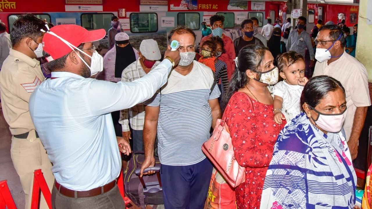 A health worker screens passengers who returned from Mumbai by Udyan Express, at Kalaburagi station on Wednesday. Maharashtra has declared a two-week-long lockdown-type measures to check rising Covid cases. Credit: DH Photo/Prashanth H G