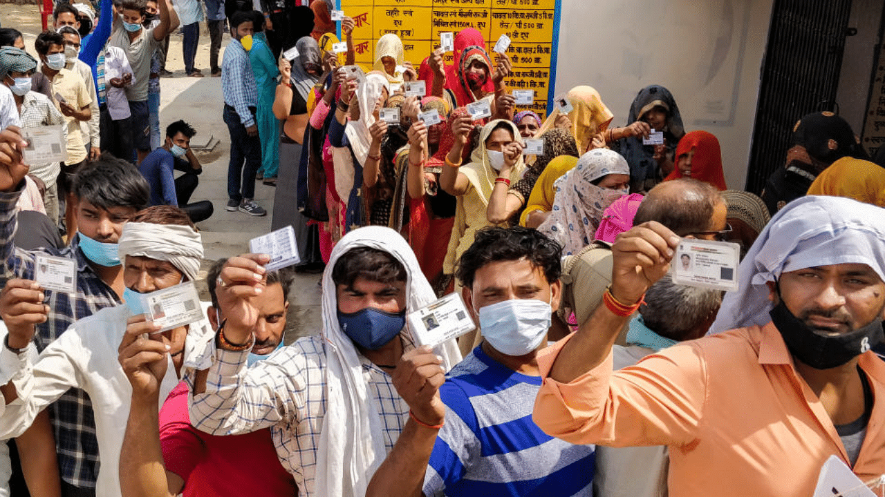 People show their voter ID as they stand in queue to cast their vote for Uttar Pradesh Gram Panchayat election, in Agra, Thursday, April 15, 2021. Credit: PTI Photo