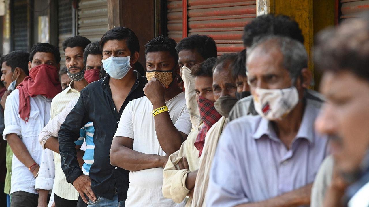 People stand in a queue as they wait for food to be distributed by social workers during weekend lockdown restrictions imposed by the state government amidst rising Covid-19 coronavirus cases, in Mumbai on April 11, 2021. Credit: AFP Photo