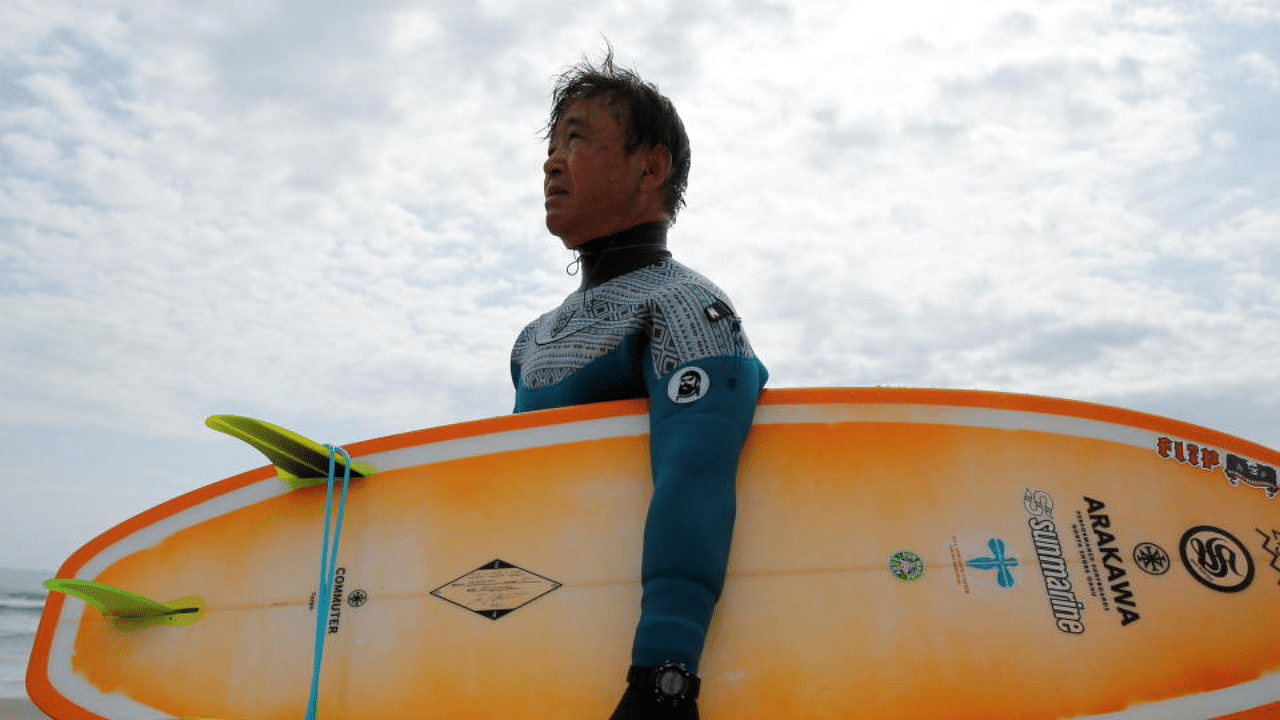 Koji Suzuki, 66, a surfer and a surf shop owner, holds his surfboard at Karasuzaki beach, around 30 kilometres (20 miles) north of the tsunami-crippled Fukushima Daiichi Nuclear Power Plant, in Minamisoma, Fukushima Prefecture, Japan, April 16, 2021.  Credit: Reuters Photo