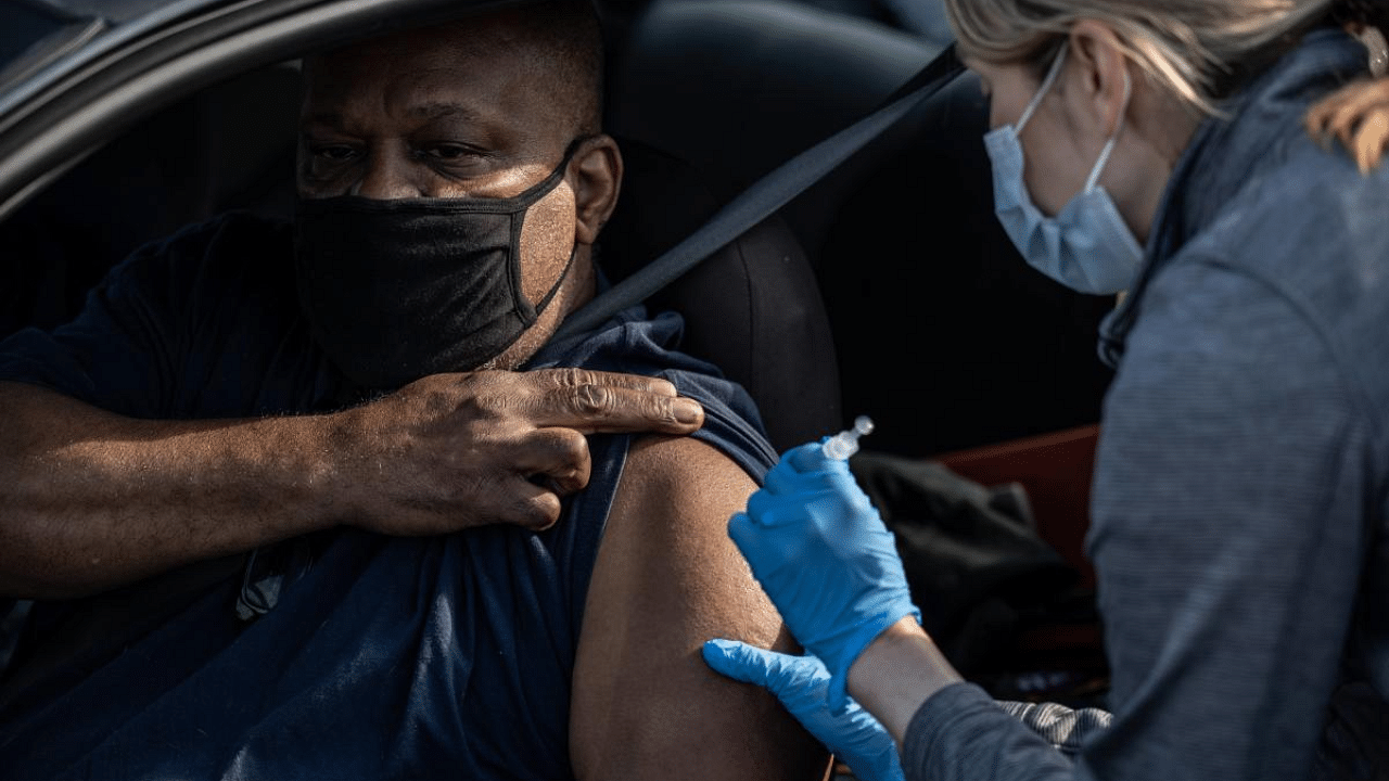 A medical professional from UofL Health administers a vaccine to a patient in their vehicle at University of Louisville Cardinal Stadium. Credit: AFP photo. 