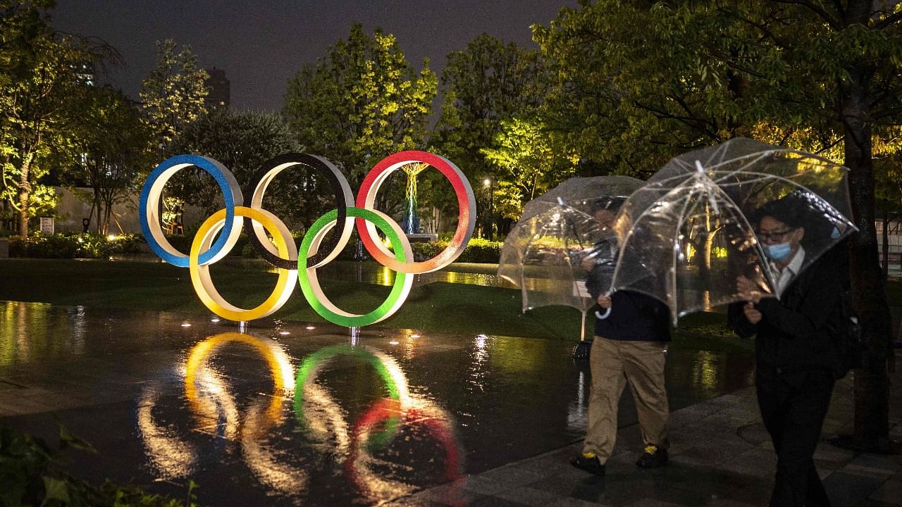 People walk past the Olympic Rings near the National Stadium, main venue for the Tokyo 2020 Olympic and Paralympic Games. Credit: AFP File Photo