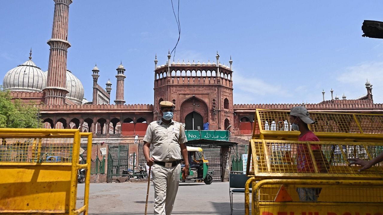 Police stand guard in the backdrop of the Jama Masjid mosque as a lockdown is in effect wherein only people catering to essential services were allowed to commute as directed by the Delhi state government to curb the spread of the Covid-19 coronavirus infections in New Delhi on April 17, 2021. Credit: AFP Photo