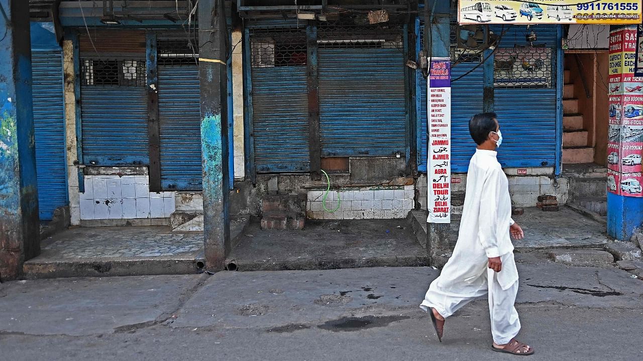 A man walks past shops with the shutters closed as a lockdown is in effect wherein only those catering to essential services were allowed to commute as directed by the Delhi state government to curb the spread of the Covid-19 coronavirus infections in New Delhi on April 17, 2021. Credit: AFP Photo