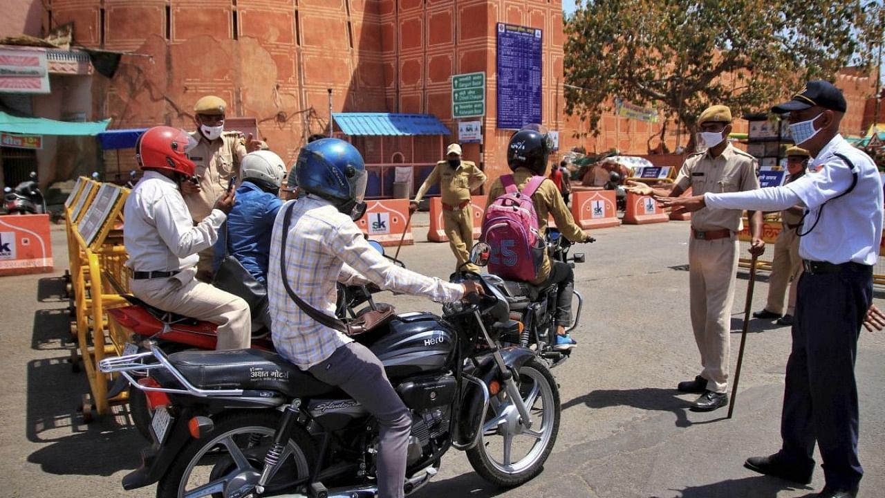 Security personnel stop commuters during the weekend curfew imposed in the wake of rising Covid-19 cases, at Chandpole Bazar in Jaipur. Credit: PTI Photo