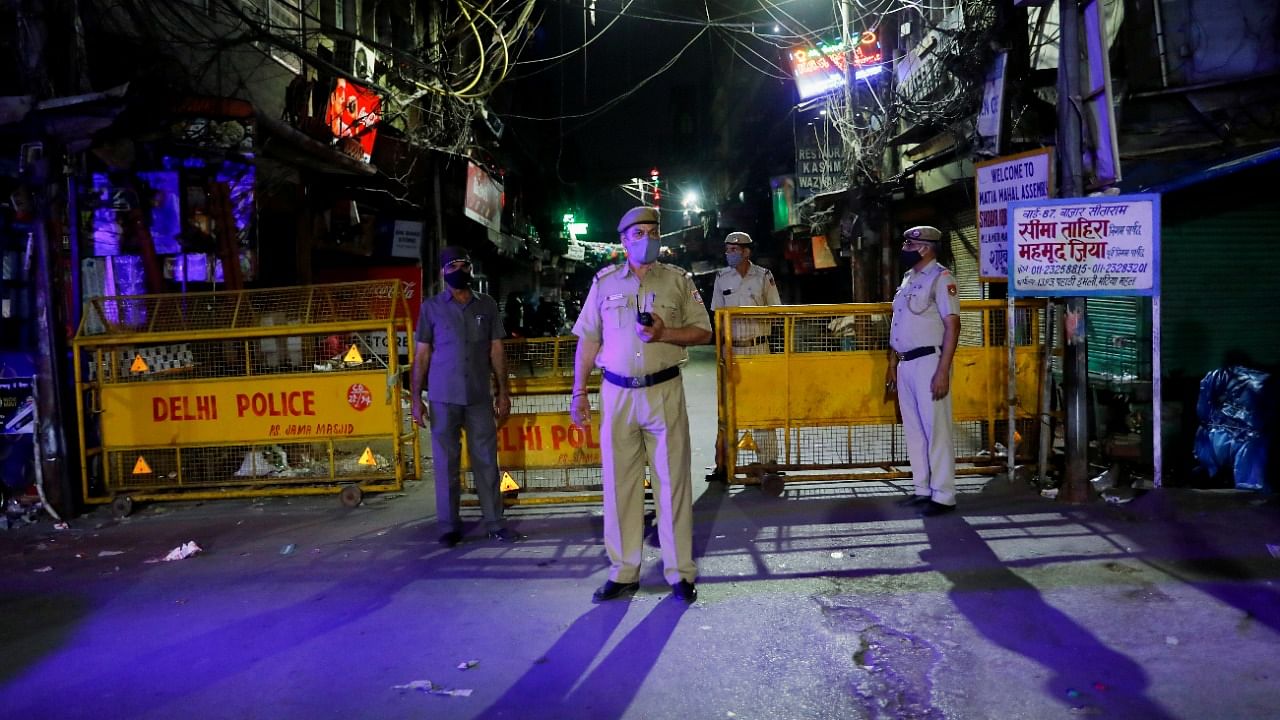 Police officers stand guard on a deserted street during a curfew to limit the spread of Covid-19, in New Delhi. Credit: Reuters photo