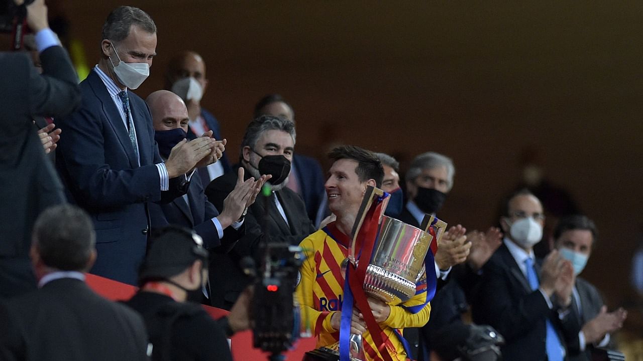 Barcelona's Argentinian forward Lionel Messi holds the trophy after receiving it from Spain's King Felipe VI (L) at the end of the Spanish Copa del Rey (King's Cup) final football match between Athletic Club Bilbao and FC Barcelona at La Cartuja stadium in Seville. Credit: AFP Photo