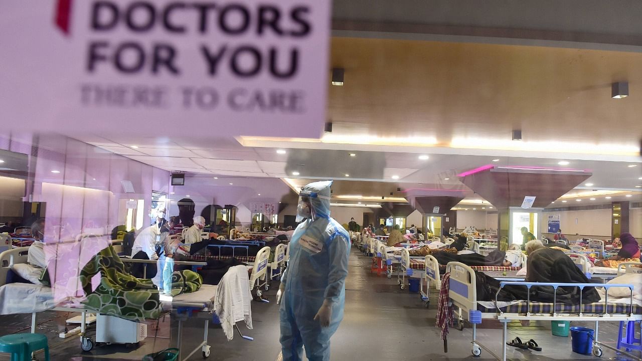 A health worker inspects Covid-19 patients undergoing treatment at Shehnai Banquet Hall, converted into an isolation centre amid surge in coronavirus cases, near LNJP Hospital in New Delhi, Sunday, April 18, 2021. Credit: PTI Photo