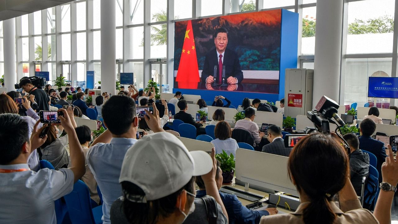 Journalists watch a screen showing China's President Xi Jinping delivering a speech during the opening of the Boao Forum for Asia (BFA) Annual Conference 2021 in Boao, south China's Hainan province on April 20, 2021. Credit: STR/AFP Photo