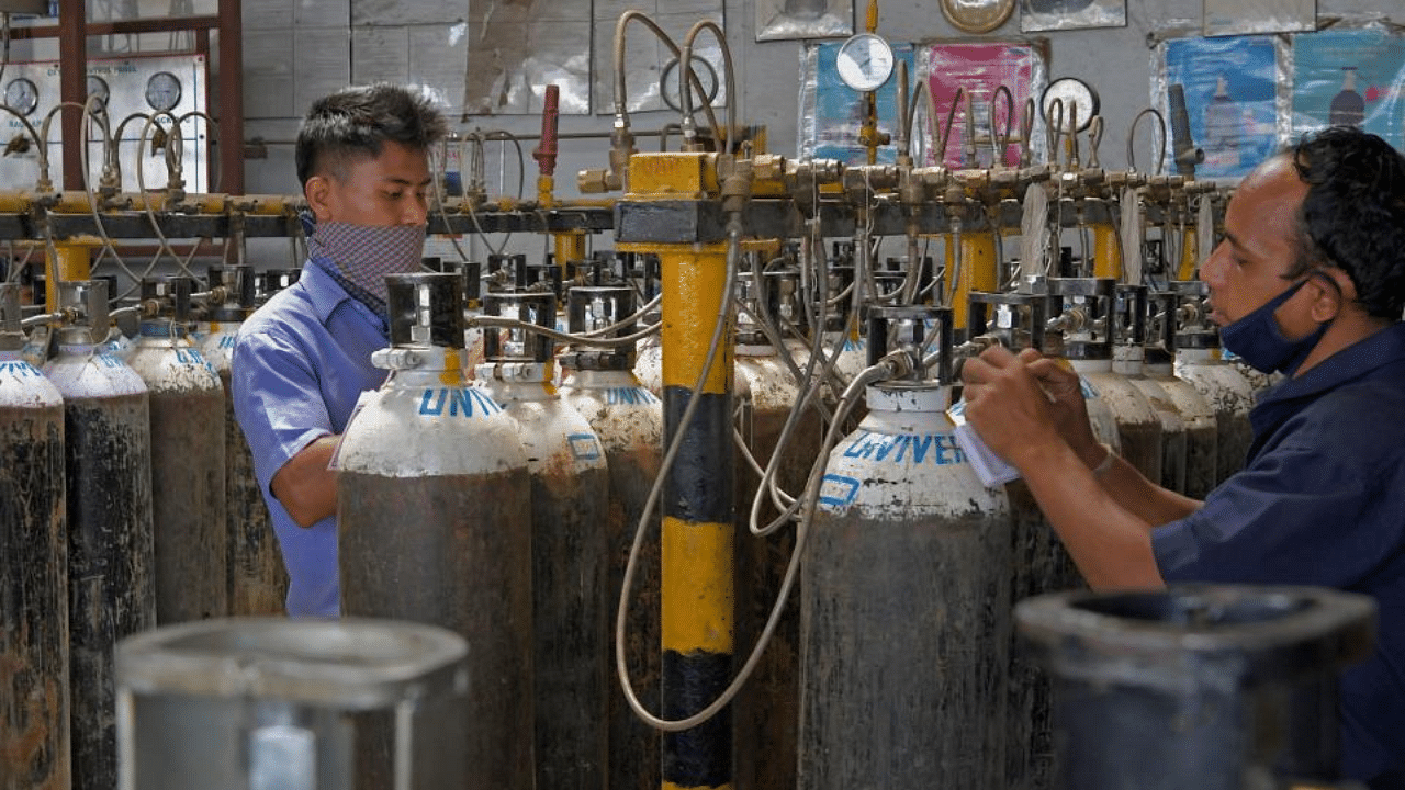 Workers are seen sorting oxygen cylinders that are being used for Covid-19 coronavirus patients before dispatching them to hospitals at a facility in Bangalore on April 19, 2021. Credit: AFP Photo